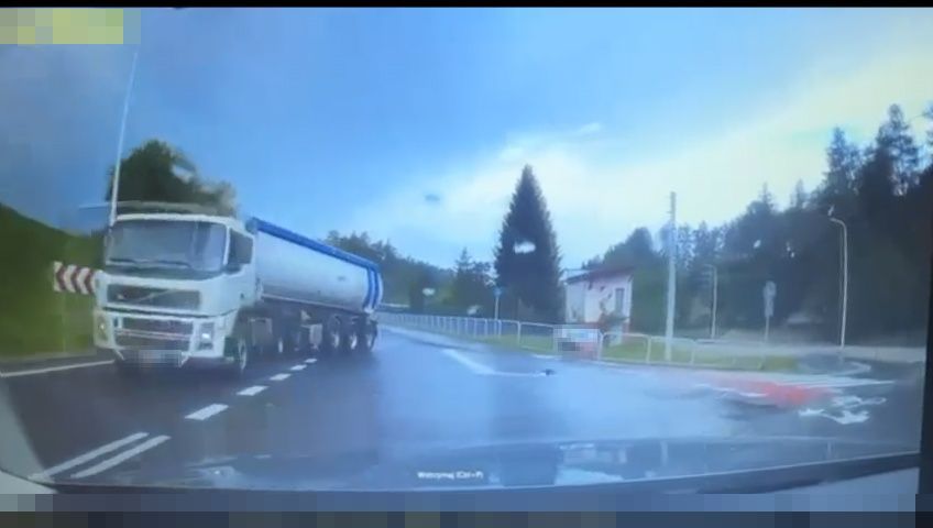 Ujęcie z rejestratora jazdy na którym widać tira, którego naczepa zachodzi na przeciwny pas drogi.