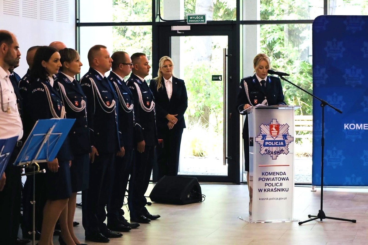 przed mównica stoi policjanta a po lewej stronie stoją policjanci