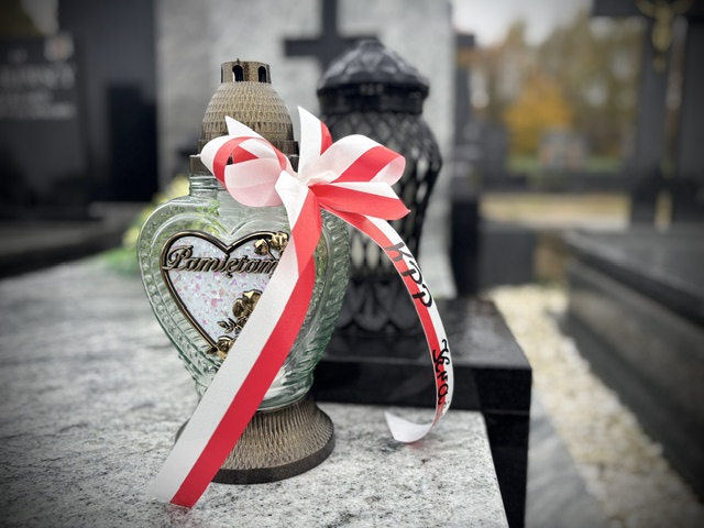 znicz z przewiązaną tasiemka w barwach biało czerwonych