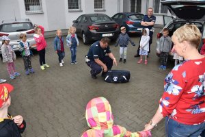 Zdjęcie przedstawia przedszkolaki z wychowawcą oraz dwóch policjantów.