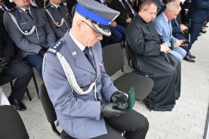 Zdjęcie przedstawia funkcjonariusza Policji oglądającego medal oraz przedstawicieli miasta oraz księdza.