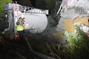 Zdjęcie przedstawia policjanta oraz przewróconą ciężarówkę.