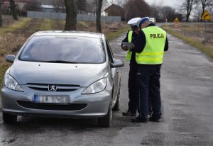 Zdjęcie przedstawia samochód osobowy oraz funkcjonariuszy Policji.