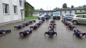 Zdjęcie przedstawia funkcjonariuszy Policji robiących pompki.