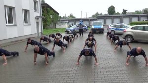 Zdjęcie przedstawia funkcjonariuszy Policji robiących pompki.