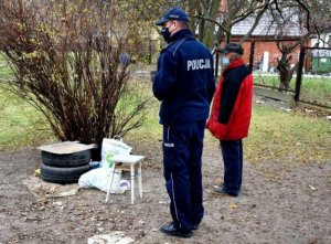 Zdjęcie przedstawia policjanta i osobę bezdomną