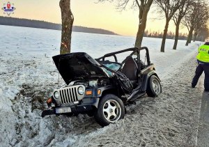 Zdjęcie przedstawia uszkodzonego Jeepa oraz policjanta