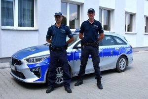 Zdjęcie przedstawia policjantów z patrolu na tle radiowozu