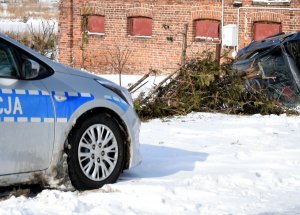 Samochód leżący na boku, obok radiowóz