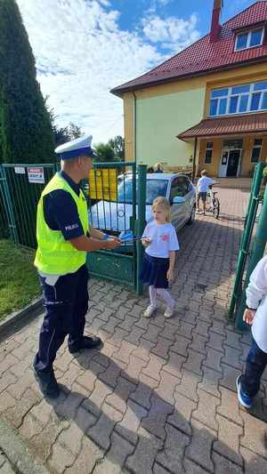 Zdjęcie przedstawia policjanta z uczniami