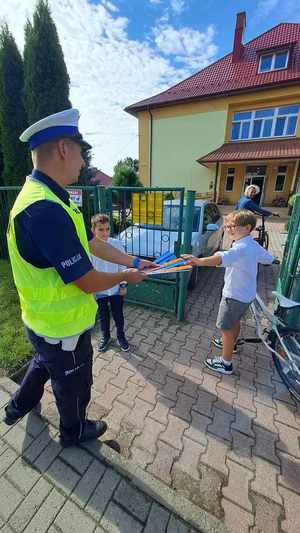 Zdjęcie przedstawia policjanta z uczniami