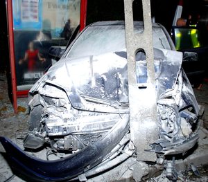 Zdjęcie uszkodzonego pojazdu i przystanku i policjant obok