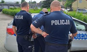 policjanci z zatrzymanym mężczyzną przy radiowozie