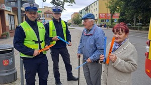 Policjanci i mieszkańcy z odblaskami na przystanku