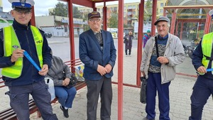 Policjanci wręczają odblaski seniorom na przystanku