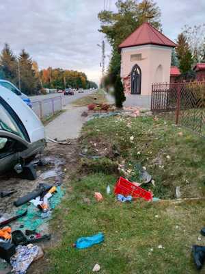 Widok na kapliczkę i rozrzucone rzeczy koło samochodu