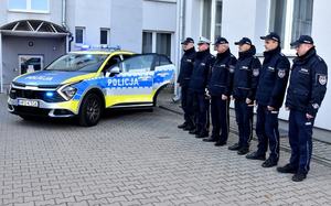 Policjanci przy radiowozie w szeregu