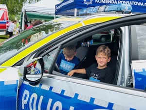 chłopcydmężczyzna w radiowoziezielnicofestyn i stoiskodziewczynka w radiowoziewy przy radiowozie wstoisko na festynie bieg po uśmiechradioprezentacja wyposażeniawozieprezentacja wycinanek przez policjanta