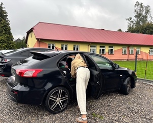 z ciemnego samochodu mama wyjmuje dziecko z fotelika