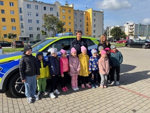 zdjęcie grupowe przedszkolaków przy radiowozie z policjantką
