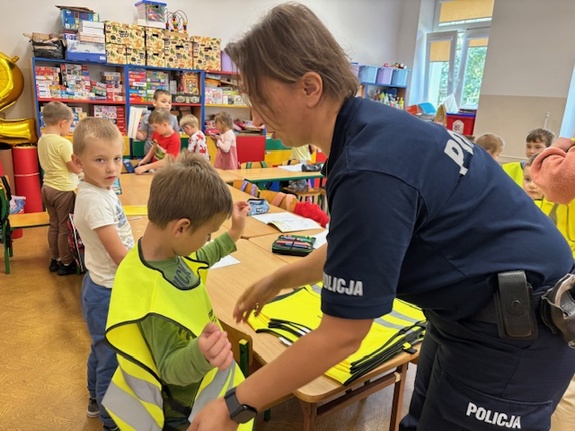policjantka zakłada dziecku kamizelkę odblaskową
