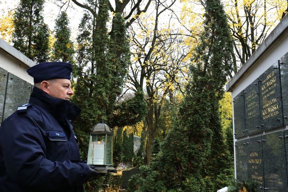 Komendant Wojewódzki Policji w Lublinie trzyma znicz przed tablicą z nazwiskami poległych funkcjonariuszy