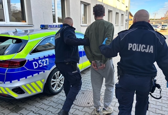 policjanci prowadzą zatrzymanego do radiowozu