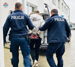 policjanci prowadzą zatrzymanego do radiowozu