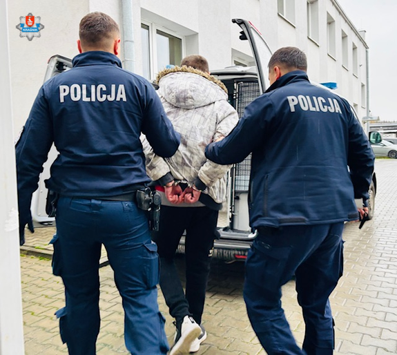 policjanci prowadzą zatrzymanego do radiowozu