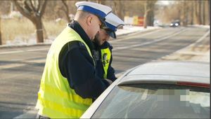 dwóch policjantów stoi przy samochodzie