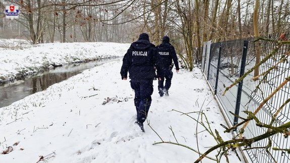 policjanci idący przy brzegu rzeki