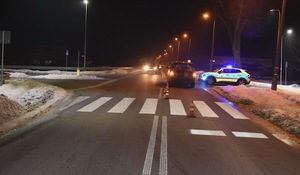 widoczne przejście dla pieszych za którym stoi samochód Land Rover a po jego prawej stronie radiowóz policyjny, po lewej stronie auta widać pas ruchu na którym policjant kieruje ruchem