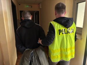 policjant prowadzi zatrzymanego mężczyznę