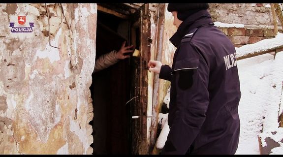 policjant otwiera drzwi do domu