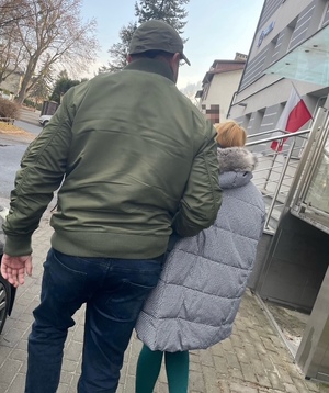 policjant prowadzi zatrzymana kobietę przed budynkiem