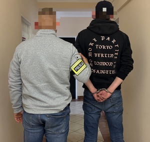policjant nieumundurowany wydziału kryminalnego  prowadzi zatrzymanego mężczyznę korytarzem