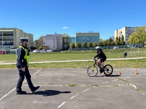 uczestnik turnieju BRD na rowerze obok stoi policjant