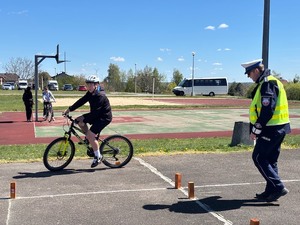 uczestnik turnieju BRD na rowerze obok stoi policjant