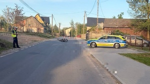 droga na której leży motocykl po prawo stoi radiowóz policyjny po lewo policjant