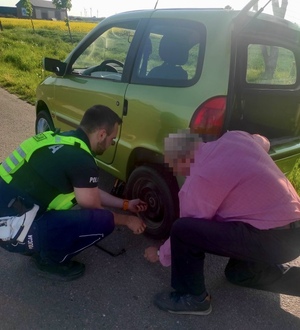 policjant odkręca koło a obok znajduje się mężczyzna