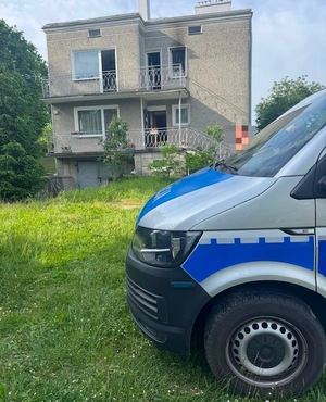 przód radiowozu policji w tyle widać murowany budynek w którym był pożar