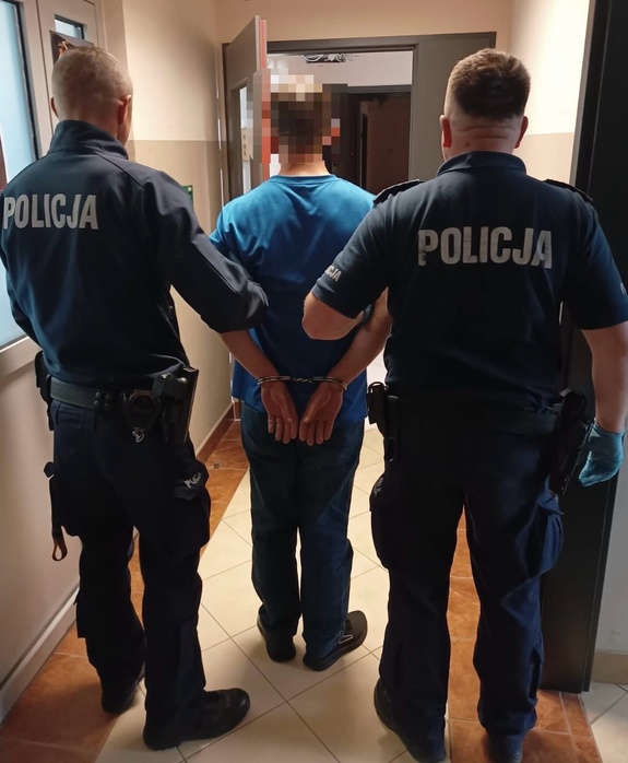 zatrzymany mężczyzna z dwoma policjantami trzyma ręce z kajdankami z tyłu
