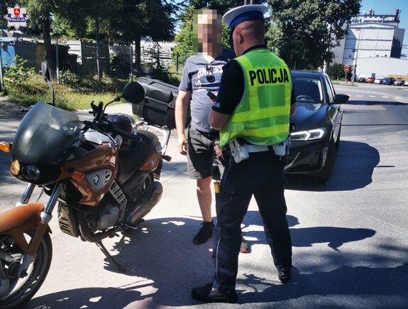policjant sprawdza dokumenty kierowcy motocykla