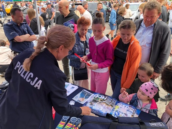 uczestnicy wydarzenia przy stoisku tyłem stoi policjantka