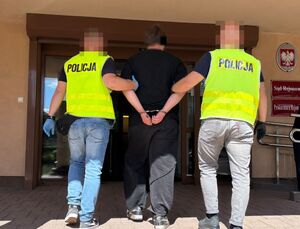 POLICJANCI PROWADZĄ ZATRZYMANEGO MĘŻCZYZNĘ