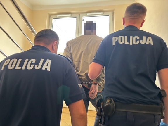 policjanci prowadzą zatrzymanego po schodach