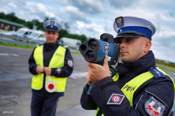 policjant dokonujący pomiaru urządzeniem koloru niebieskiego