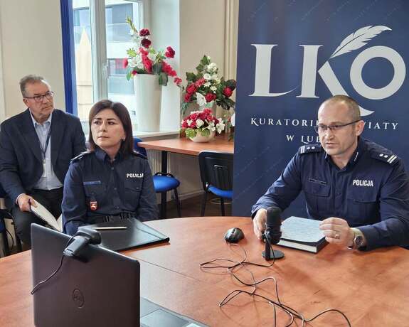 po prawej stronie przy stole siedzi Komendant Miejski Policji w Lublinie po lewej stronie przy stole siedzi policjantka a za nią mężczyzna
