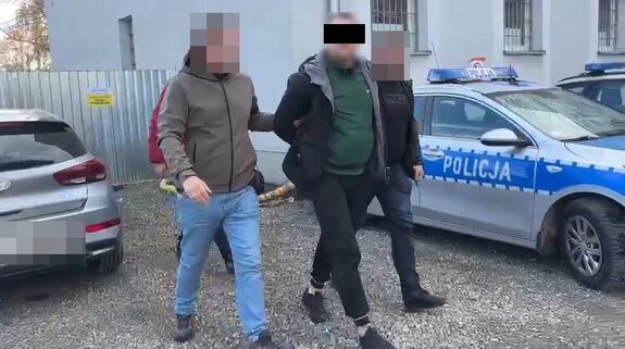 Policjanci prowadzą zatrzymanego mężczyznę.