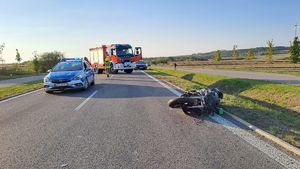 miejsce wypadku, motocykl leżący na jezdni, w tle radiowóz i wóz strażacki